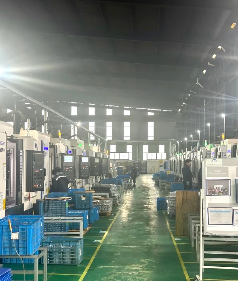 Rows of CNC vertical machining centers along a green-marked production aisle